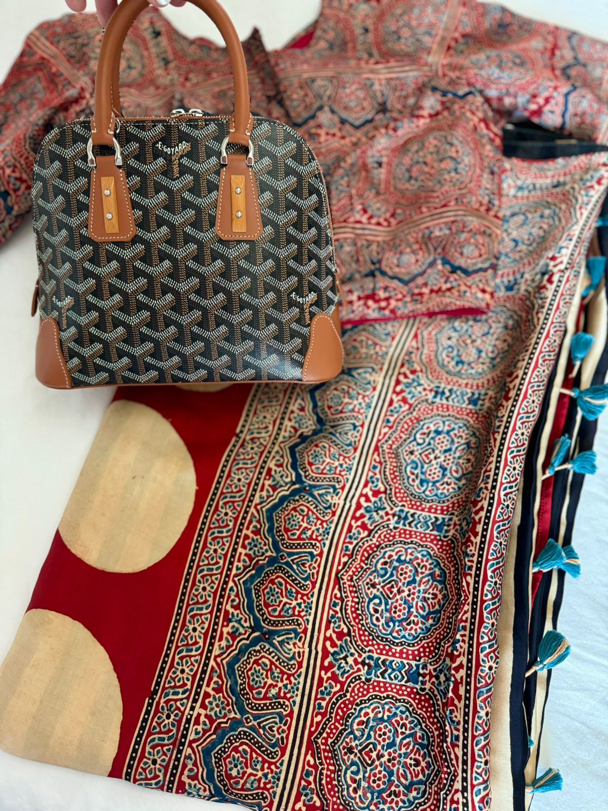 Kawaii ajrakh saree with intricate red and blue traditional patterns alongside a stylish brown and black handbag